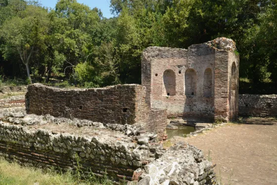 Stone walls and columns of the Triconch Palace among trees at the ancient ruins of Butrint, southern Albania