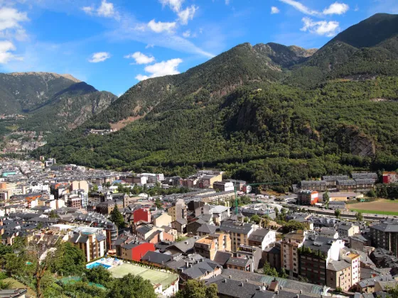 The town of Andorra la Vella filling a narrow valley floor, with forested Pyrenean slopes rising steeply on either side