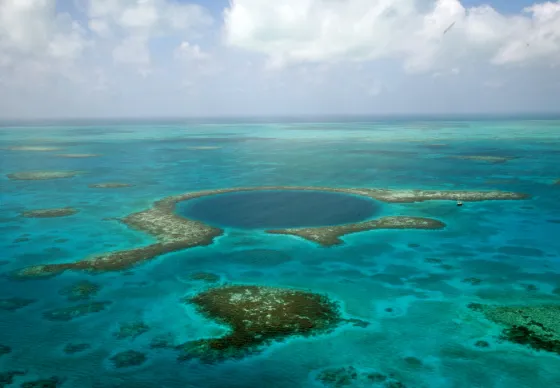Aerial view of the Great Blue Hole, a giant circular marine sinkhole off the coast of Belize, surrounded by the pale turquoise water of the surrounding reef