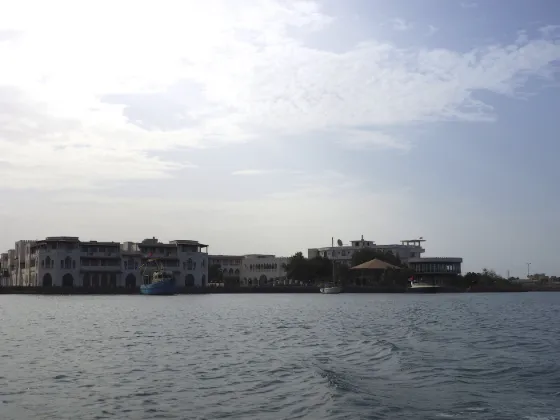 Low waterfront buildings of the old port of Massawa seen across calm Red Sea water, Eritrea