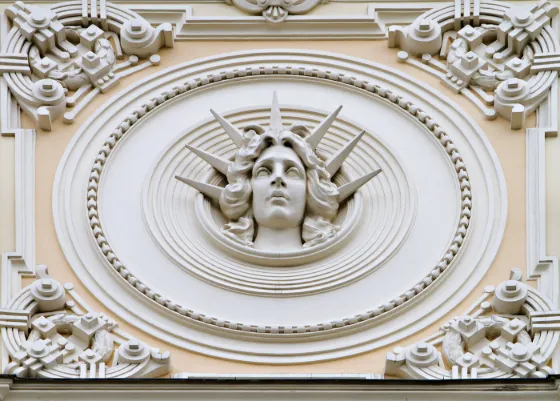 An ornate plaster face and wreath moulded into the Art Nouveau facade of a building in central Riga