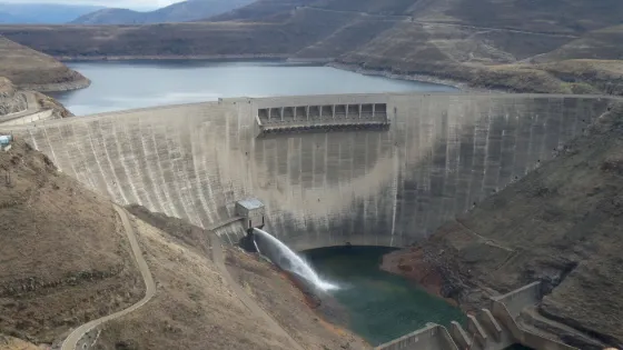 The curved concrete wall of Katse Dam holding back its reservoir between bare Lesotho highlands