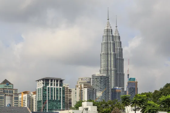 The twin steel spires of the Petronas Towers rising above the Kuala Lumpur skyline under cloud