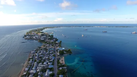The narrow strip of Majuro Atoll seen from the air, houses lining the land between the lagoon and the open Pacific