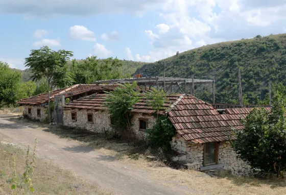 Stone houses with tiled roofs below bare hills at Orheiul Vechi, Moldova