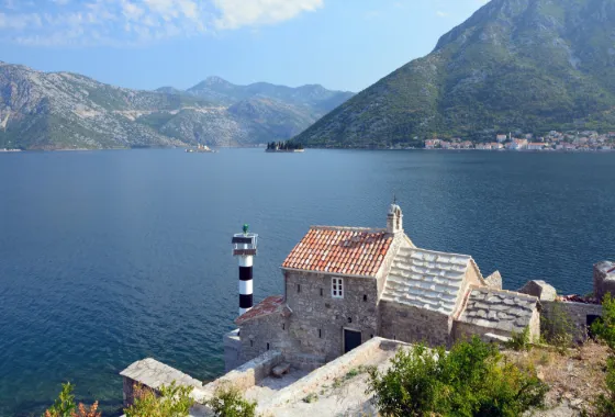 The islet church of Our Lady of the Rocks in the Bay of Kotor, with steep grey mountains rising behind