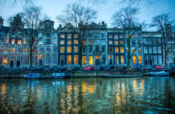 Canal houses reflected in an Amsterdam canal at dusk