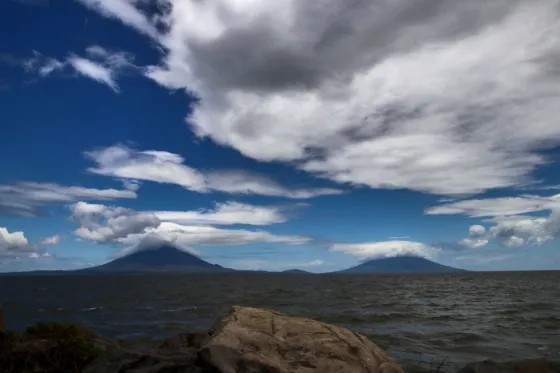 The twin volcanic cones of Ometepe island rising across the open water of Lake Nicaragua under heavy cloud