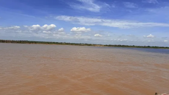 The wide brown Niger River under a bright sky, with low vegetated banks in the distance