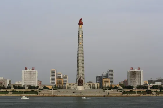 The Juche Tower with its red flame finial rising above apartment blocks along the river in Pyongyang