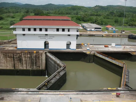 A lock chamber and control house at the Miraflores Locks on the Panama Canal, with forested hills behind