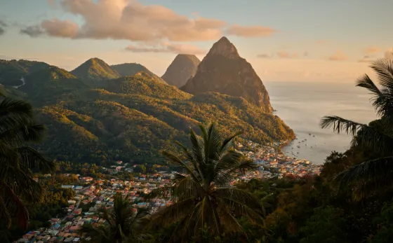 The two forested volcanic spires of the Pitons rising above Soufriere and the sea at sunset, Saint Lucia