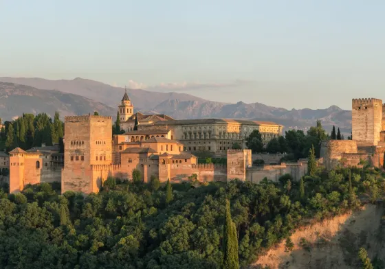 The Alhambra, a Moorish palace-fortress complex in Granada, Spain, at sunset with the Sierra Nevada mountains behind it