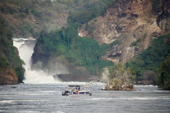 The Nile forcing through a narrow gorge at Murchison Falls, with a small boat on the water below
