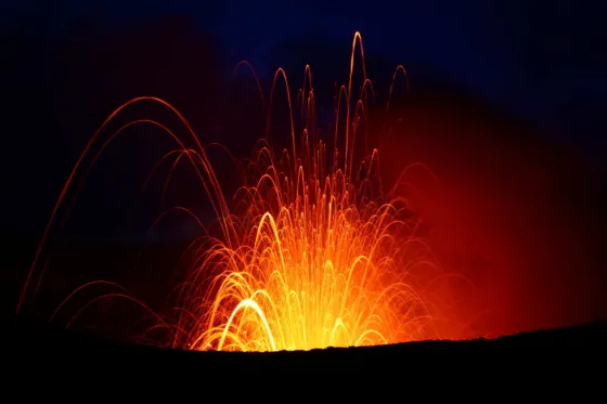 Molten lava fountaining in bright orange arcs from the crater of Mount Yasur at night, Tanna, Vanuatu