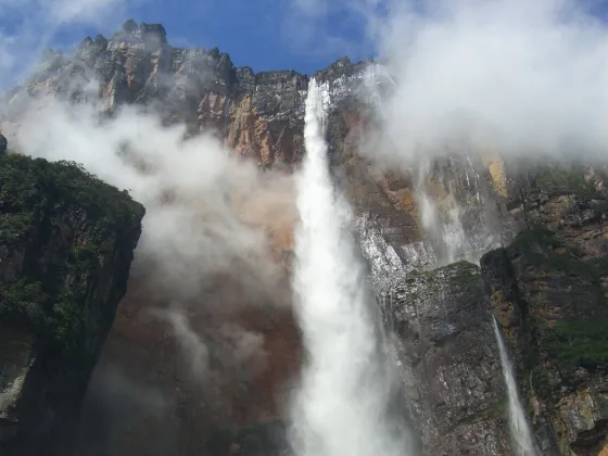 Angel Falls dropping in a long white thread from a sheer cliff into mist and forest, Venezuela