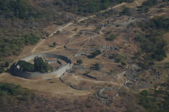 The curved stone walls and enclosures of the medieval city of Great Zimbabwe seen from the air, set in dry hills